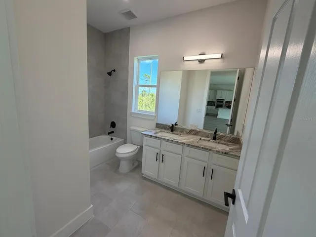 a bathroom with a granite countertop sink a toilet and a mirror