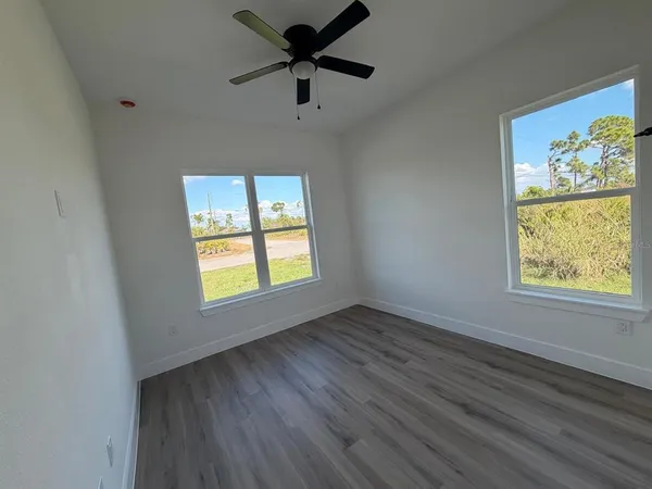 a view of an empty room with a window and wooden floor