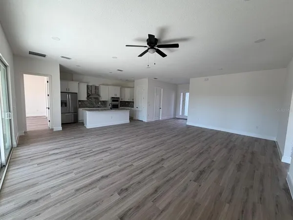 a view of a big room with wooden floor and windows