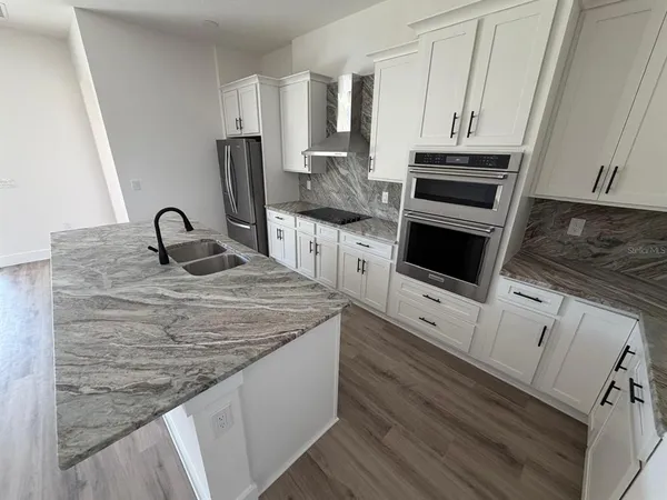 a kitchen with granite countertop a sink stove and cabinets
