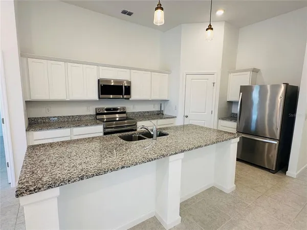 a kitchen with stainless steel appliances granite countertop a refrigerator a stove a sink and a microwave