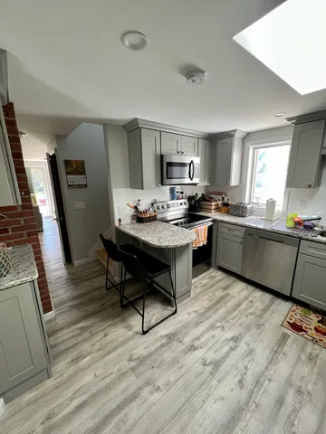 a living room with stainless steel appliances kitchen island granite countertop furniture a rug a stove a sink and a refrigerator