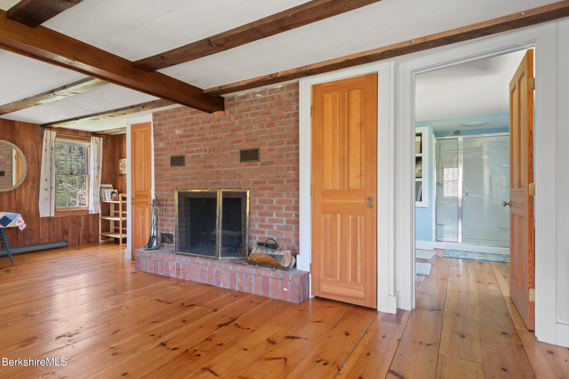 350 Beartown Mountain Road Monterey, MA 01245 - Photo 28 of 38 an empty room with wooden floor a fireplace and windows