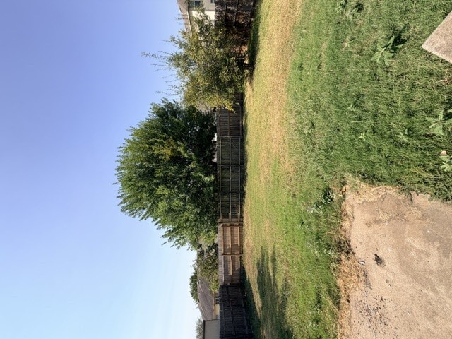 18421 Crestwind Lane Elgin, TX 78621 - Photo 33 of 34 A spacious grassy lawn is fully enclosed by a tall wooden privacy fence.