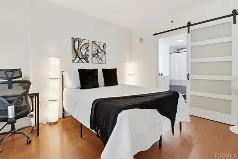 a bedroom with a walk in closet and wooden floor