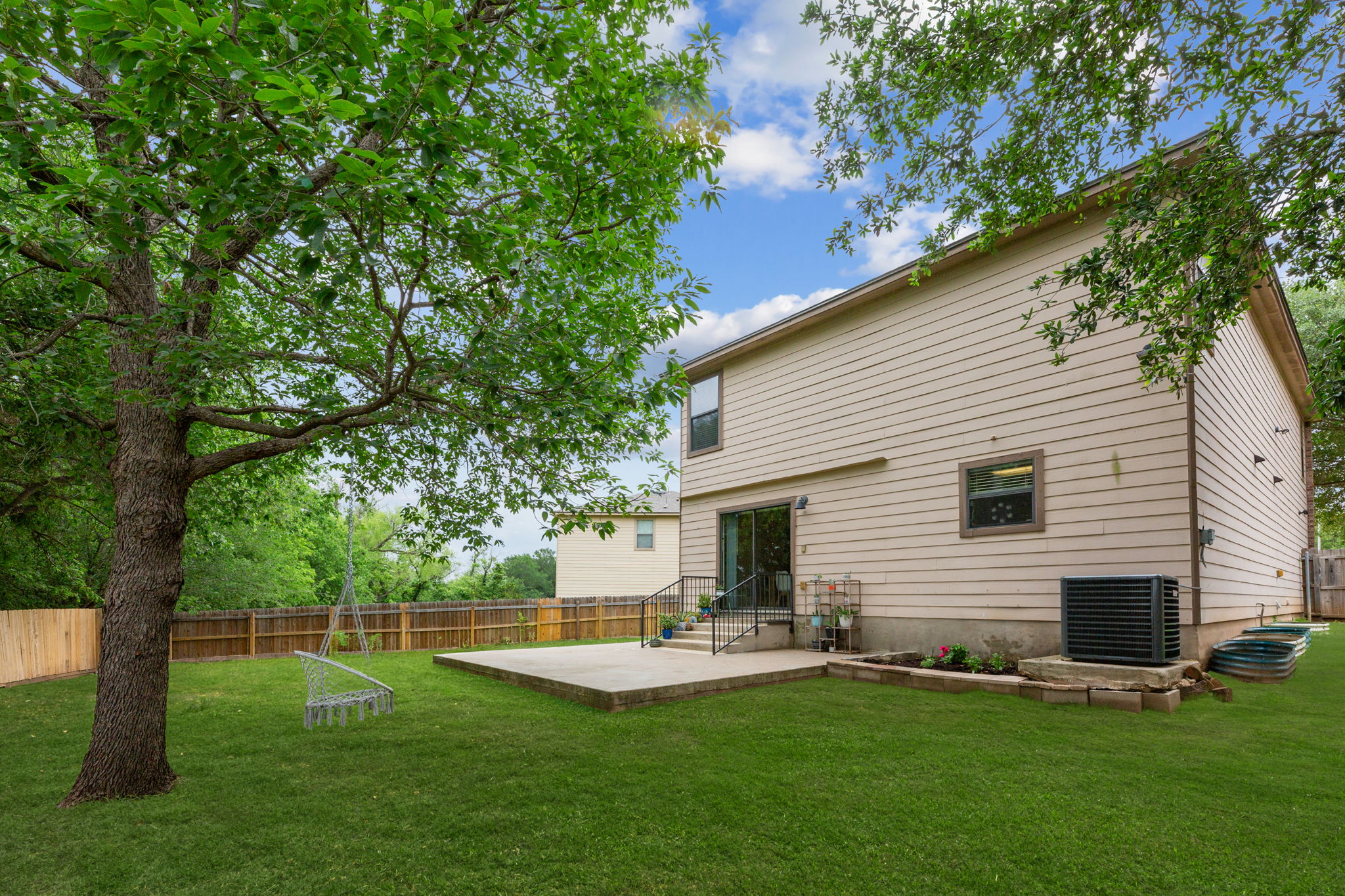 310 Myrtle Street Kyle, TX 78640 - Photo 27 of 40 Expansive backyard featuring a large mature tree, full privacy fencing, and a ground-level concrete patio with direct access to the home (green grass photography)