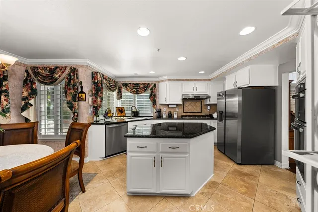 a kitchen with stainless steel appliances granite countertop a refrigerator a sink a stove and chairs