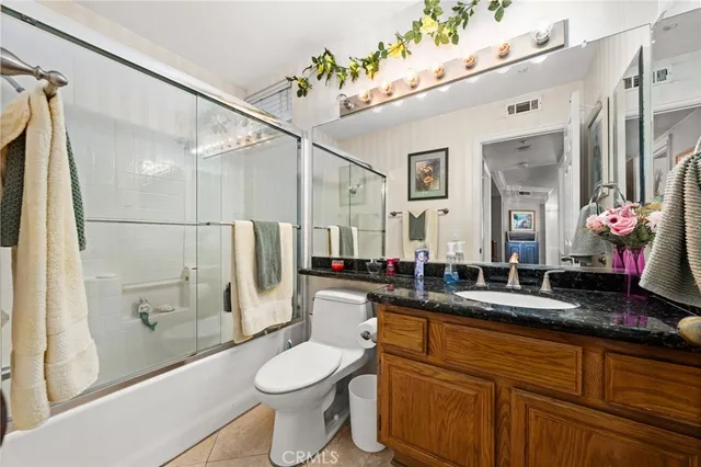 a bathroom with a granite countertop sink a toilet a mirror and shower