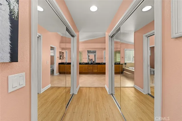 a view of a hallway with wooden floor a glass door and a living room