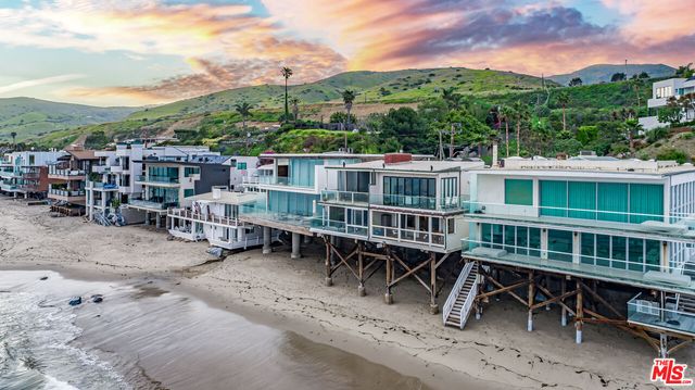 a view of a house with a wooden deck and a forest