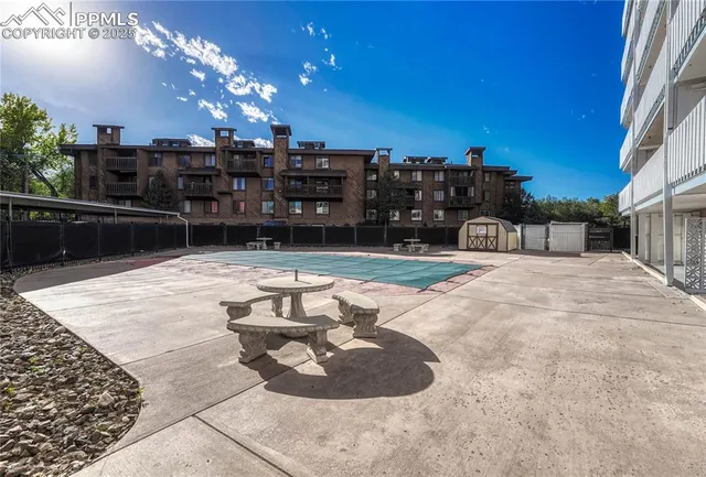 a view of swimming pool with seating space and trees in the background
