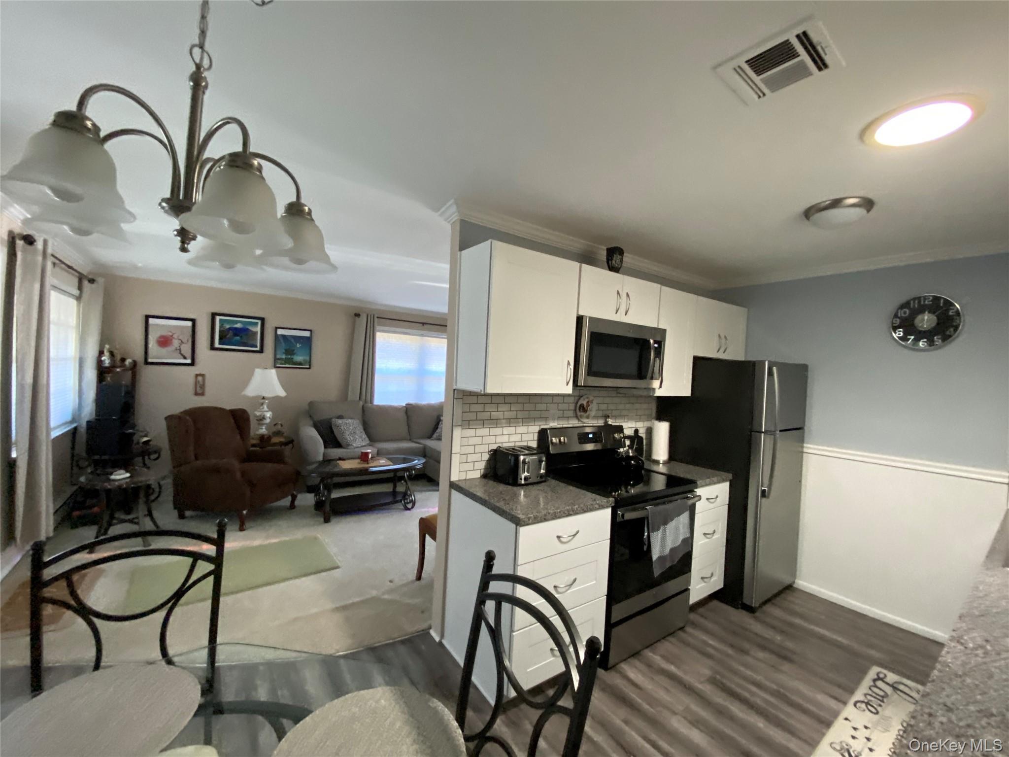 274 Berwick Court, Unit A Ridge, NY 11961 - Photo 31 of 31 Kitchen featuring electric range oven, open floor plan, white cabinets, stainless steel microwave, and tasteful backsplash