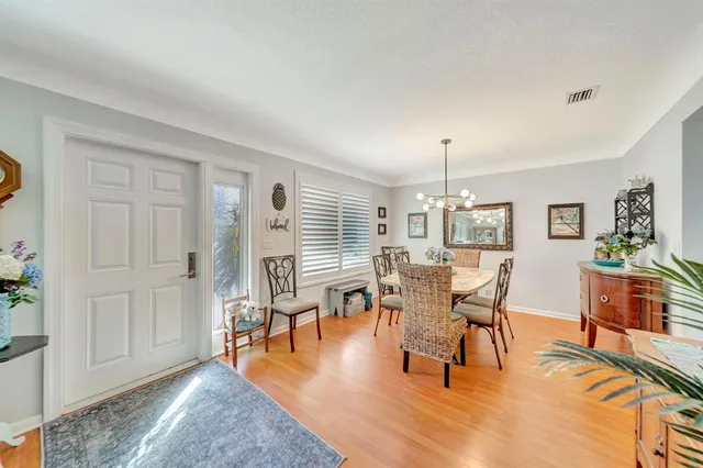 a dining room with wooden floor a chandelier a wooden table and chairs