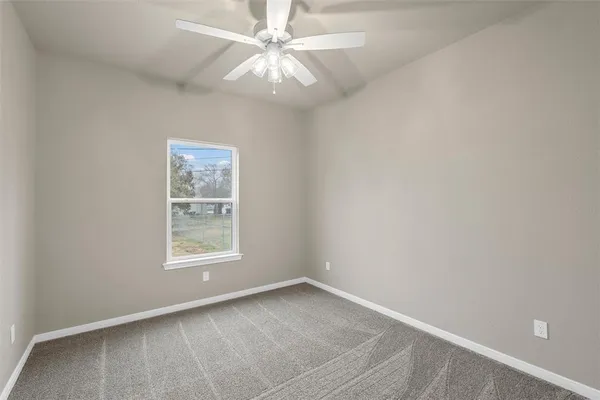 an empty room with a window and a fan