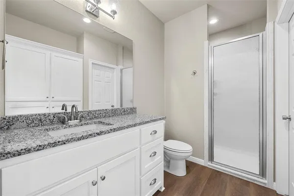 a bathroom with a granite countertop sink a toilet and a shower