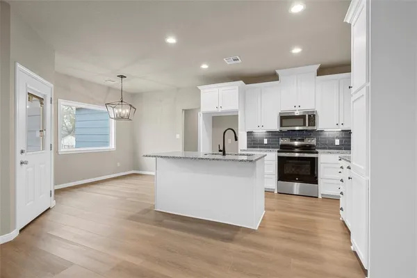 a kitchen with stainless steel appliances kitchen island granite countertop a stove a sink and a refrigerator