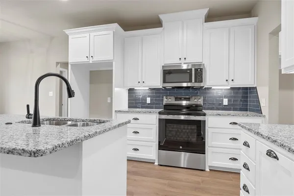 a kitchen with granite countertop a stove and a microwave