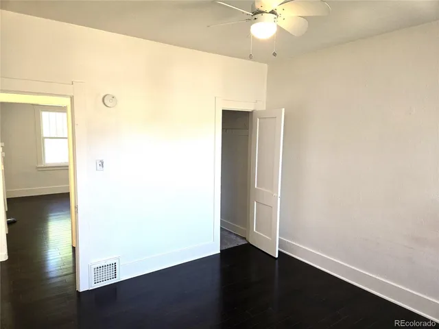 an empty room with wooden floor and fan