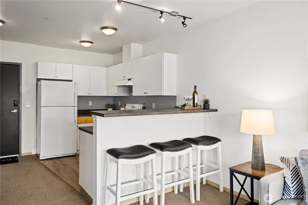 a kitchen with stainless steel appliances granite countertop a table chairs stove and refrigerator