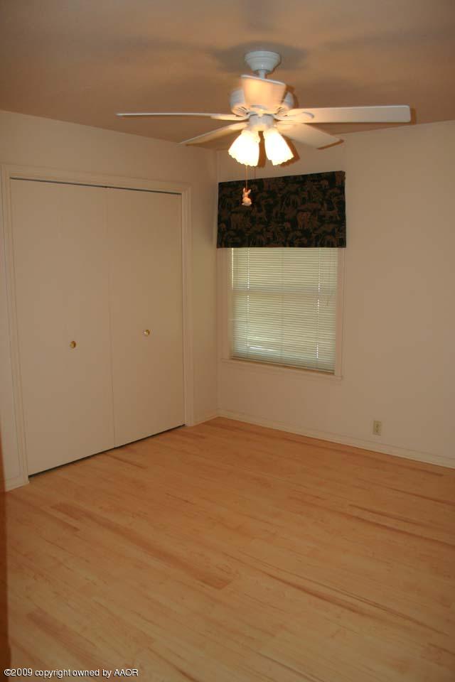 6904 Elmhurst Road Amarillo, TX 79106 - Photo 11 of 15 an empty room with a chandelier fan and windows