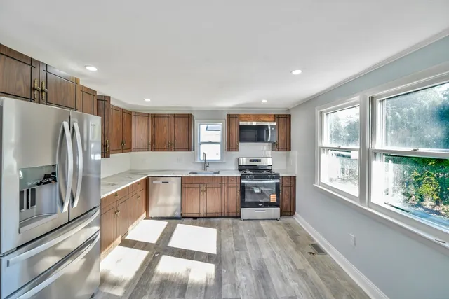 a kitchen with stainless steel appliances granite countertop a refrigerator oven a sink dishwasher and a stove with wooden floor