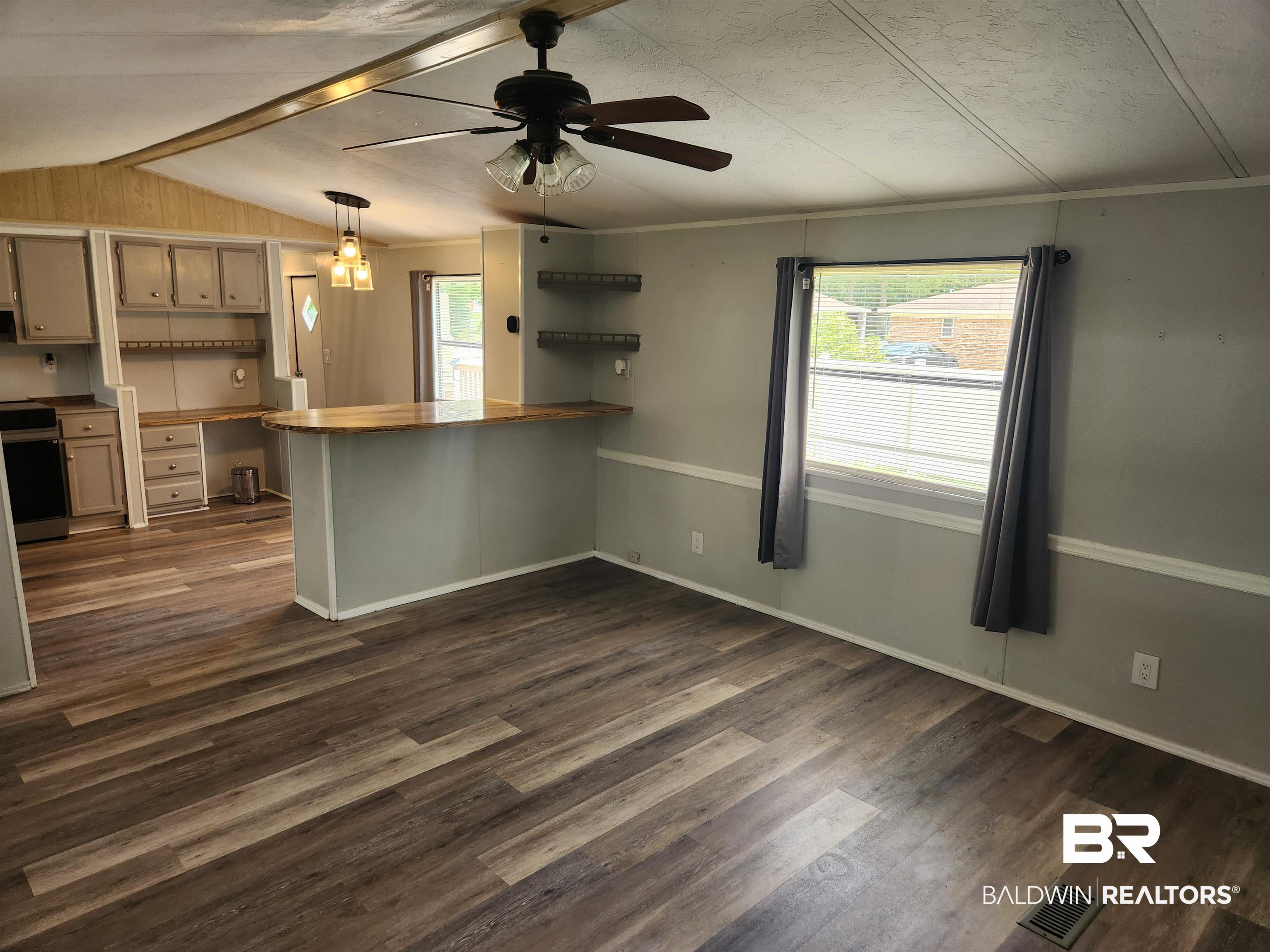 23051 Fritz Lane Foley, AL 36535 - Photo 16 of 26 Open-concept living space featuring wood-finish flooring, a ceiling fan, and a kitchen bar with pendant lighting