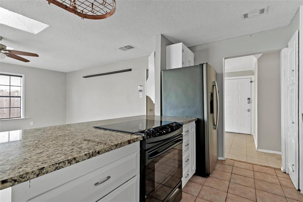6104 Kelly Elliott Road Arlington, TX 76001 - Photo 16 of 25 a kitchen with granite countertop a refrigerator and a stove