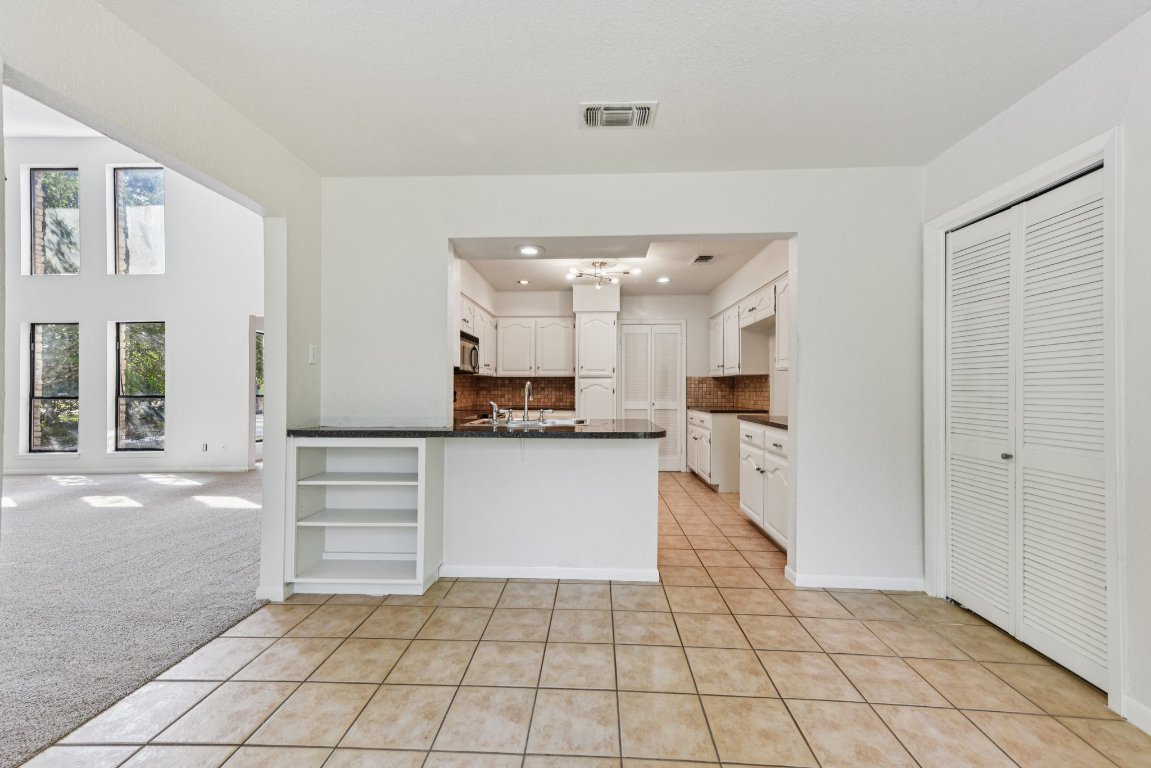 503 Hackberry Street Lockhart, TX 78644 - Photo 16 of 36 Kitchen with light tile patterned flooring, tasteful backsplash, a peninsula, white cabinets, and light carpet