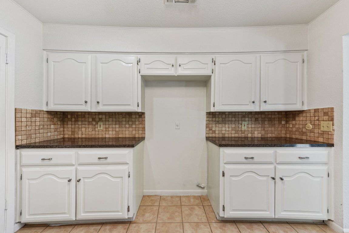 503 Hackberry Street Lockhart, TX 78644 - Photo 17 of 36 Kitchen with white cabinetry, light tile patterned floors, backsplash, ornamental molding, and a textured ceiling