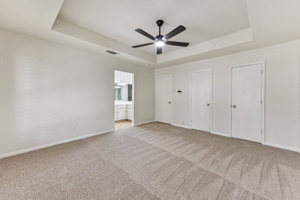 503 Hackberry Street Lockhart, TX 78644 - Photo 26 of 36 Unfurnished bedroom with a tray ceiling, light carpet, and multiple closets