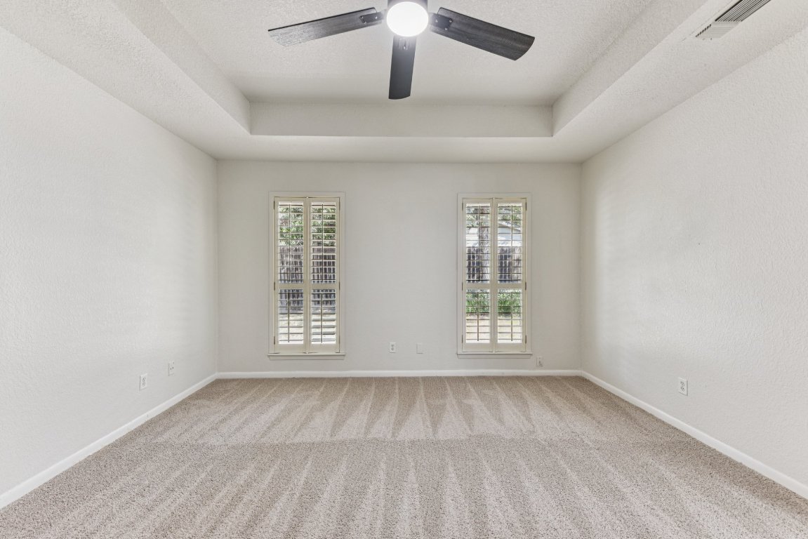 503 Hackberry Street Lockhart, TX 78644 - Photo 27 of 36 Empty room with a raised ceiling, light carpet, a textured wall, a textured ceiling, and a ceiling fan
