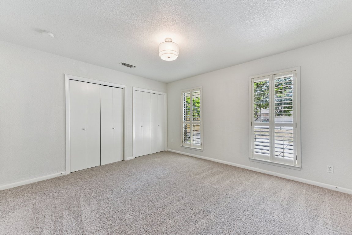 503 Hackberry Street Lockhart, TX 78644 - Photo 5 of 36 Unfurnished bedroom with multiple closets, light carpet, and a textured ceiling