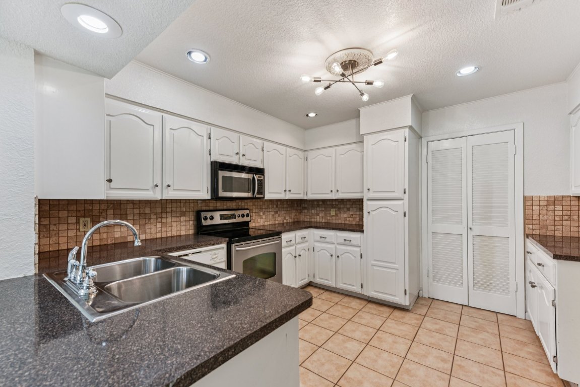503 Hackberry Street Lockhart, TX 78644 - Photo 6 of 36 Kitchen with white cabinetry, decorative backsplash, light tile patterned floors, a textured ceiling, and appliances with stainless steel finishes