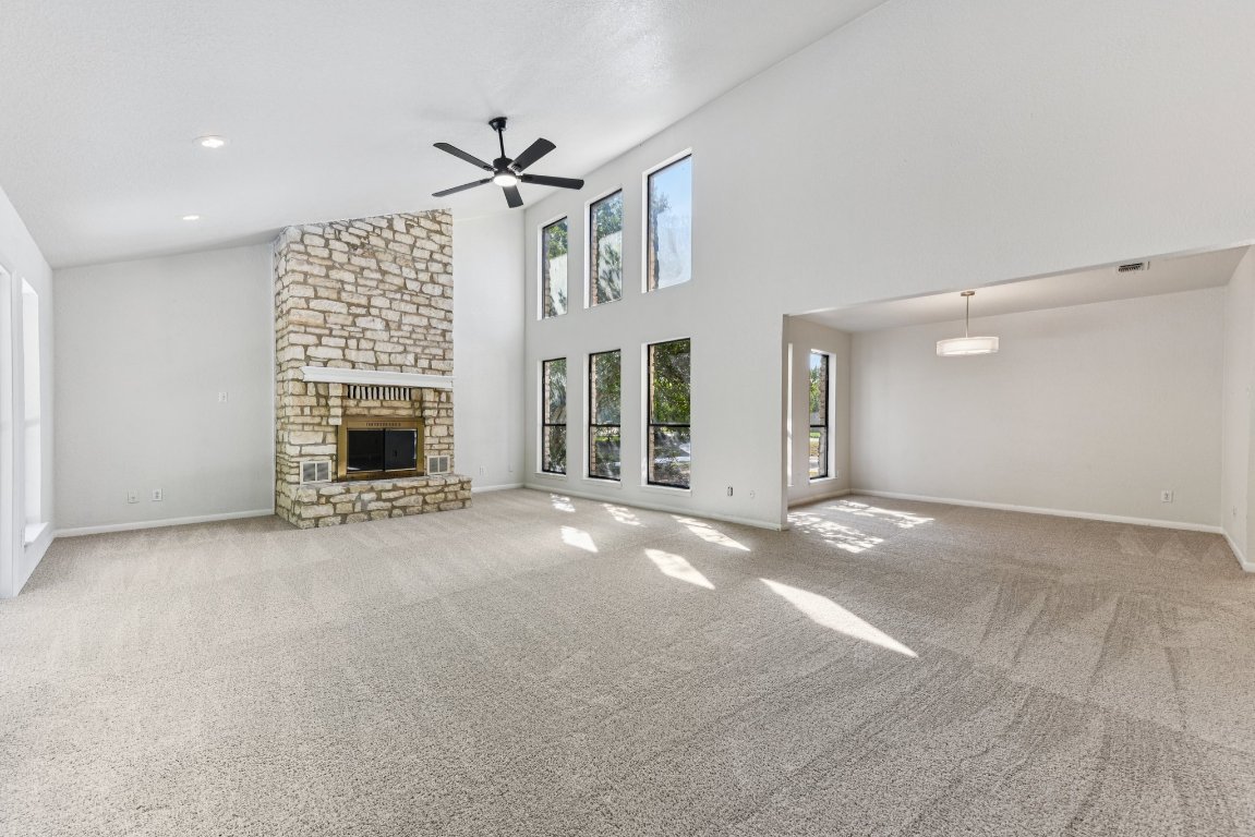 503 Hackberry Street Lockhart, TX 78644 - Photo 10 of 36 Unfurnished living room with light carpet, a fireplace, a towering ceiling, and ceiling fan