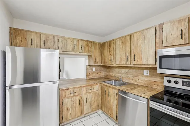a kitchen with stainless steel appliances granite countertop a refrigerator a stove and a sink