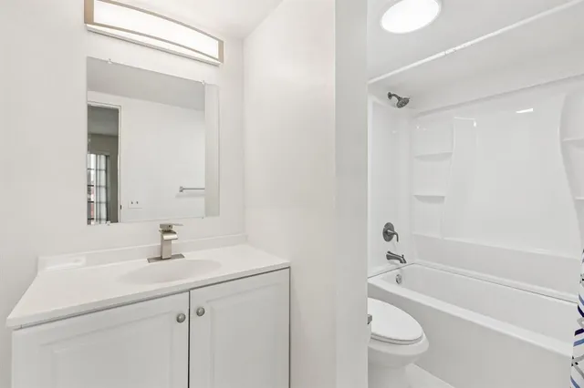 a bathroom with a bathtub shower sink vanity mirror and toilet