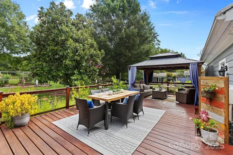 a view of a patio with dining table and chairs couches with wooden floor and fence