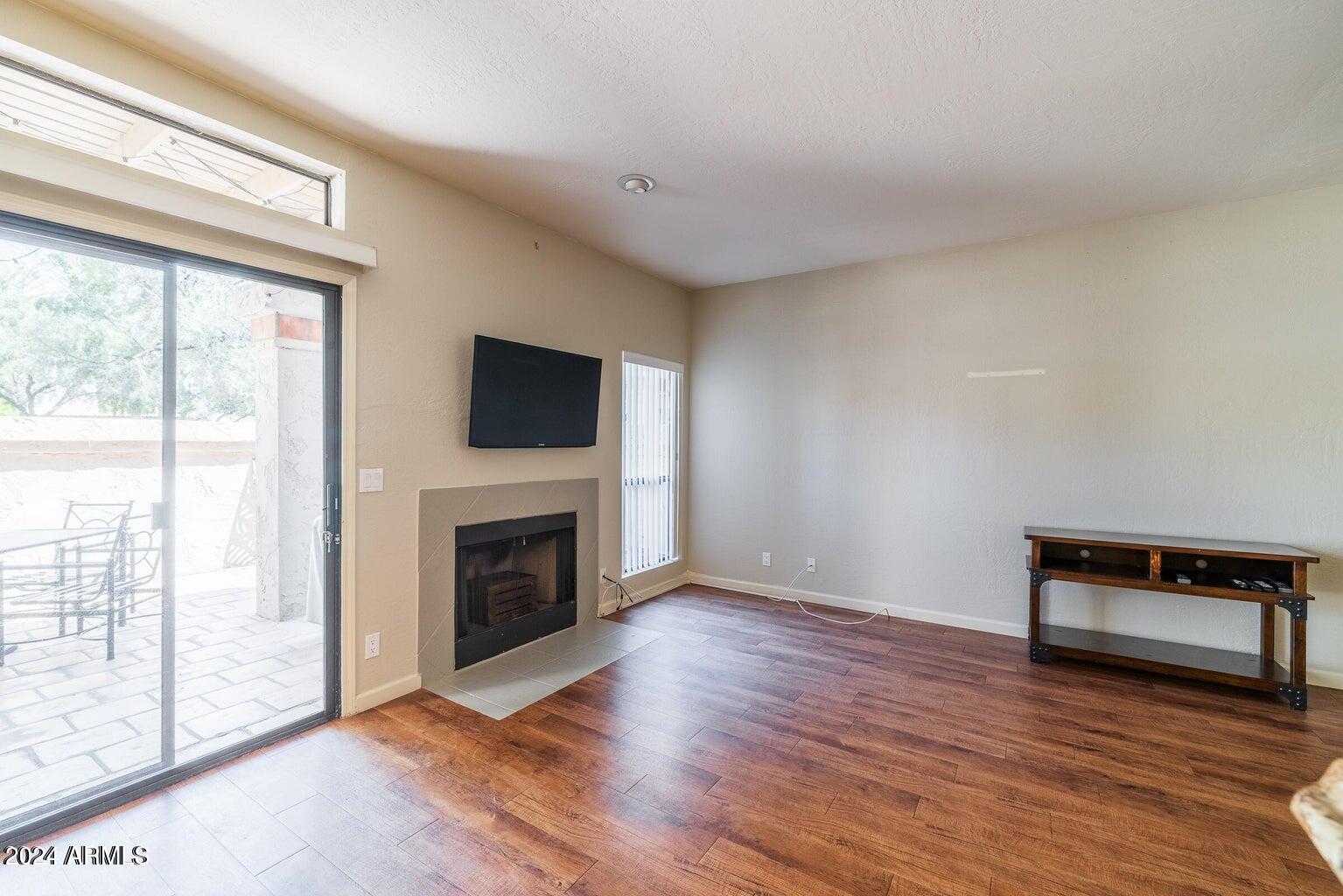 9705 East Mountain View Road, Unit 1021 Scottsdale, AZ 85258 - Photo 5 of 14 a view of an empty room with wooden floor fireplace and a window