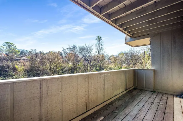 a view of a balcony with wooden floor and fence