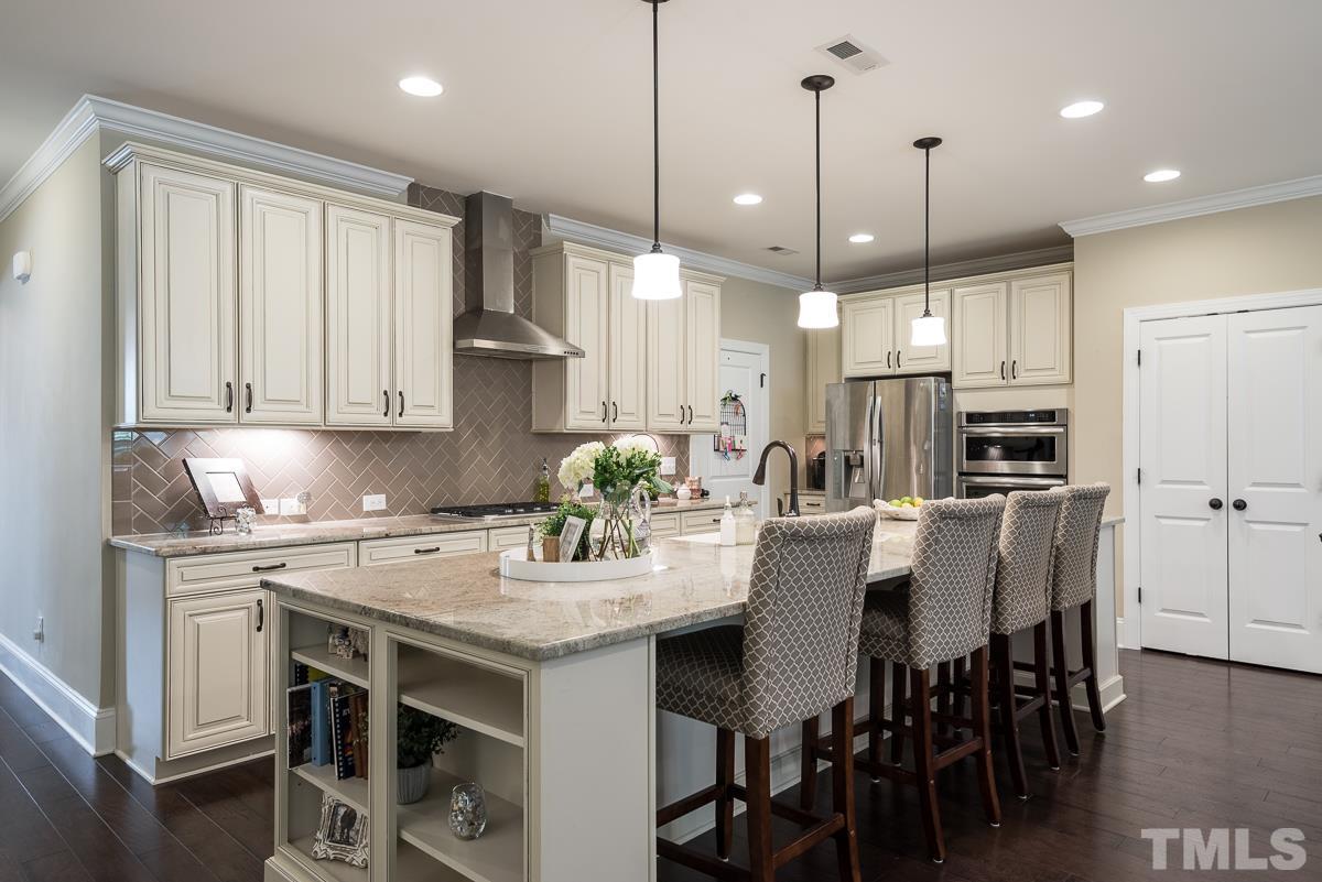 4025 Periwinkle Blue Lane Raleigh, NC 27612 - Photo 5 of 23 a kitchen with kitchen island granite countertop a table chairs sink and cabinets
