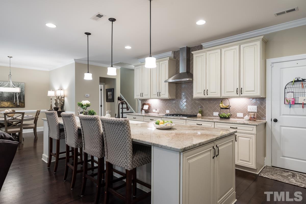 4025 Periwinkle Blue Lane Raleigh, NC 27612 - Photo 6 of 23 a kitchen with stainless steel appliances granite countertop a stove a sink a center island a refrigerator and white cabinets