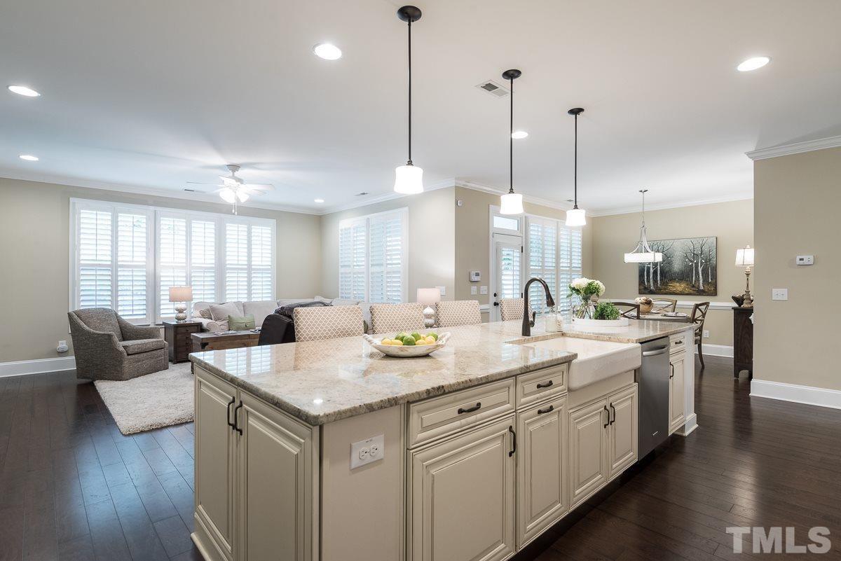 4025 Periwinkle Blue Lane Raleigh, NC 27612 - Photo 7 of 23 a kitchen with center island white cabinets and a wooden floor