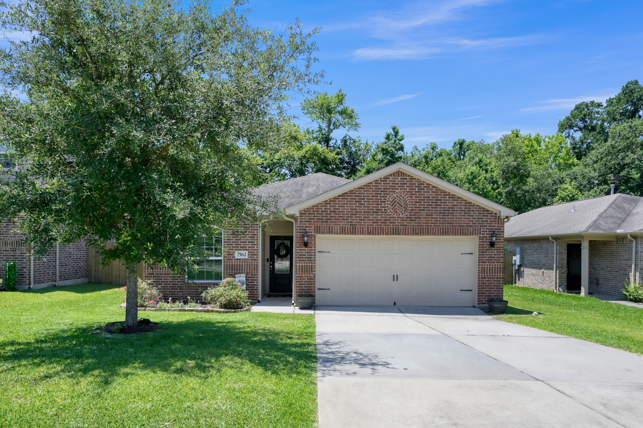 7562 Fettle Lane Conroe, TX 77304 - Photo 3 of 30 Beautiful front elevation featuring spacious driveway, mature tree, and inviting curb appeal.