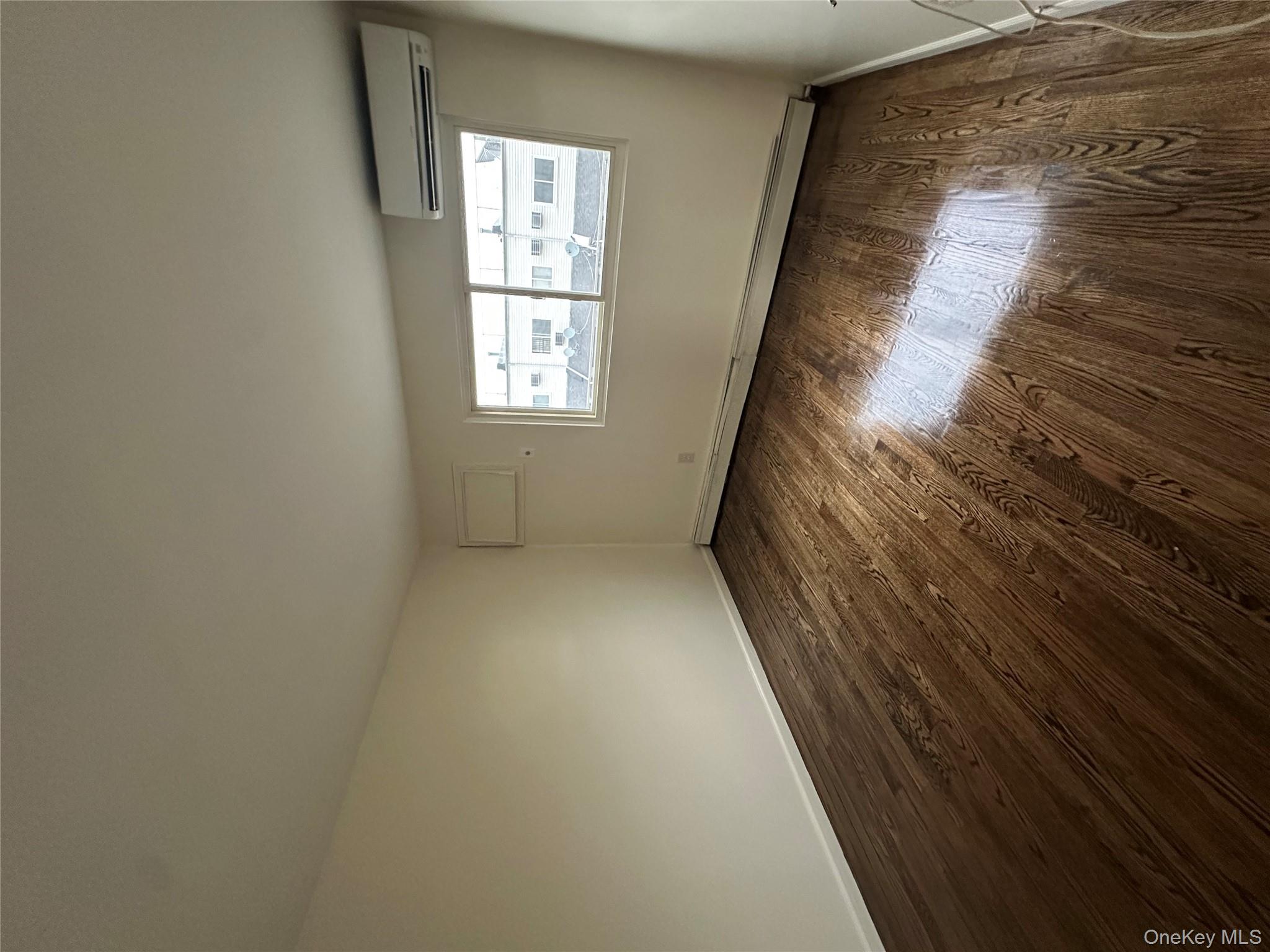 987 Lincoln Avenue, Unit 2 Brooklyn, NY 11208 - Photo 4 of 7 an empty room with wooden floor and windows