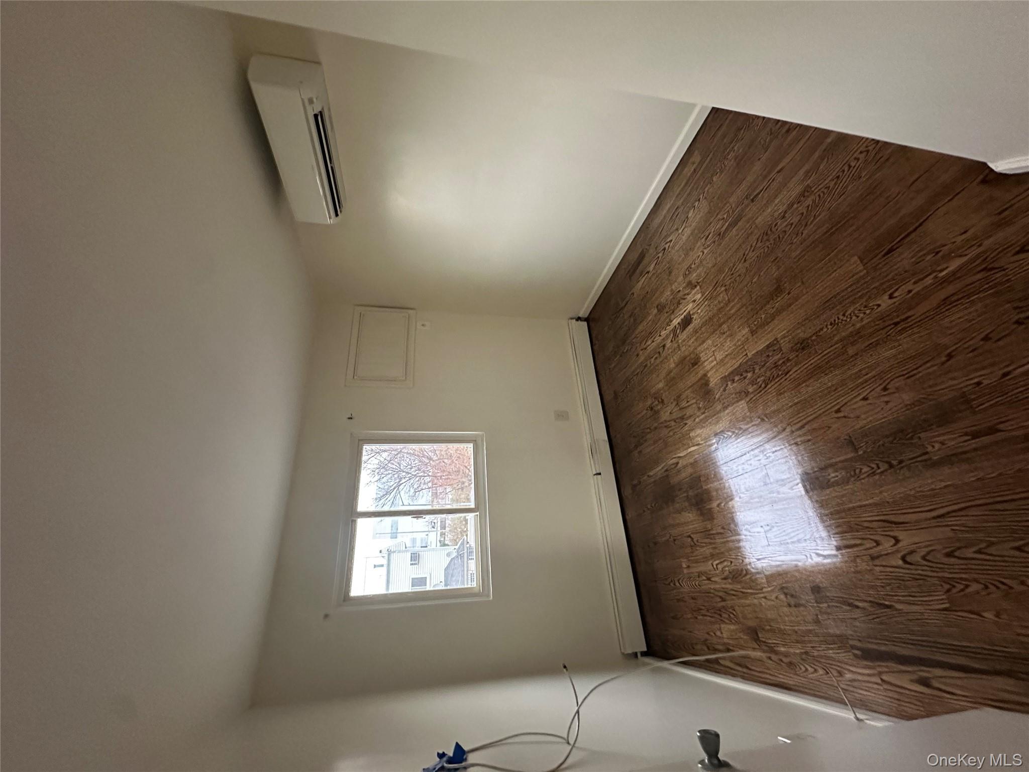 987 Lincoln Avenue, Unit 2 Brooklyn, NY 11208 - Photo 5 of 7 an empty room with wooden floor and windows