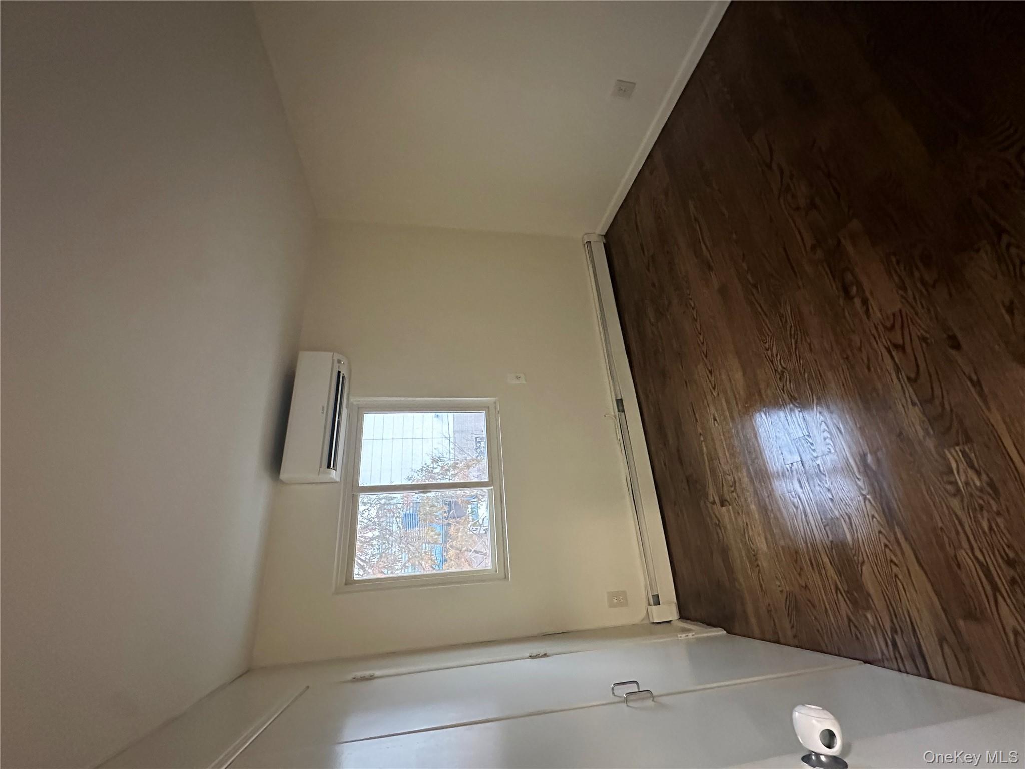987 Lincoln Avenue, Unit 2 Brooklyn, NY 11208 - Photo 6 of 7 an empty room with wooden floor and windows