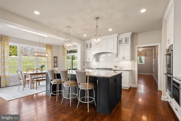 a kitchen with stainless steel appliances granite countertop a table chairs stove and wooden floor