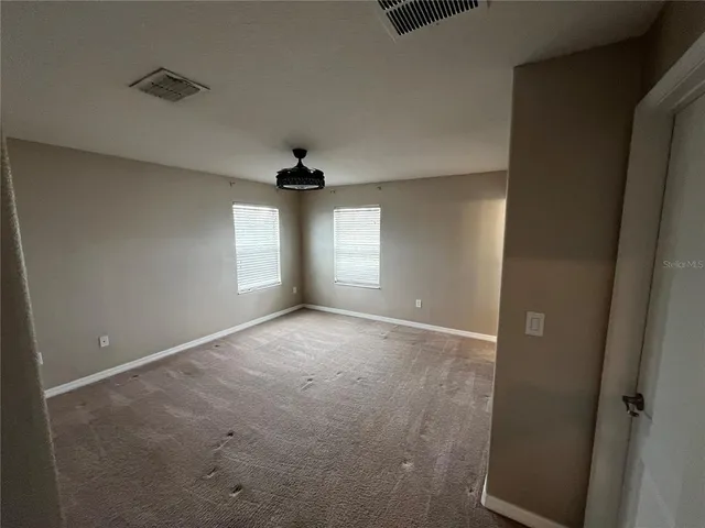 an empty room with windows and ceiling fan