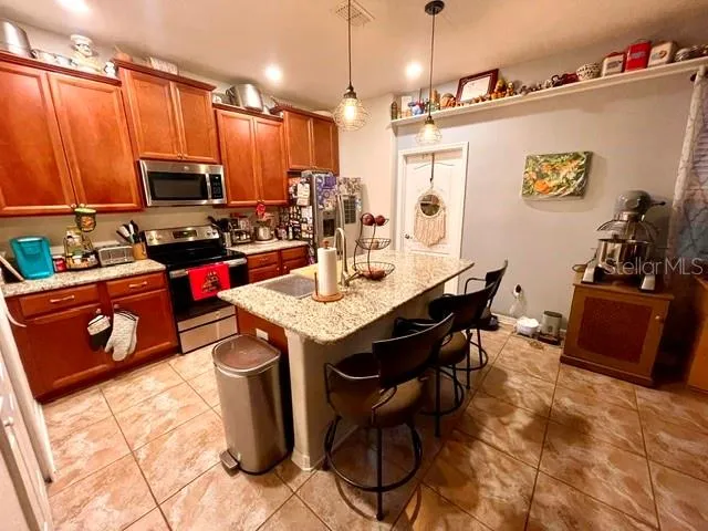 a kitchen with stainless steel appliances granite countertop a refrigerator a sink dishwasher a stove and a dining table with wooden floor