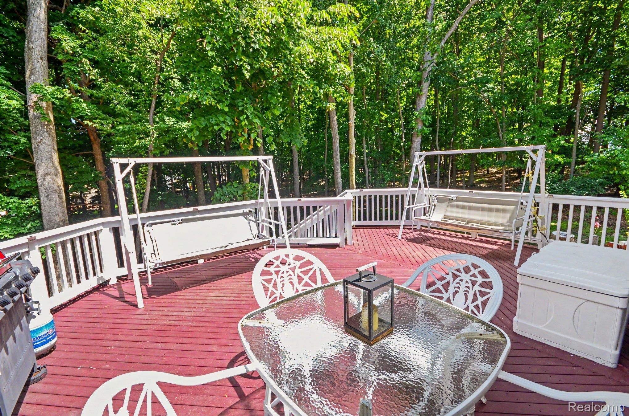 425 Thornridge Court Rochester, MI 48307 - Photo 28 of 35 Expansive red-stained deck with white railing, framed by mature trees